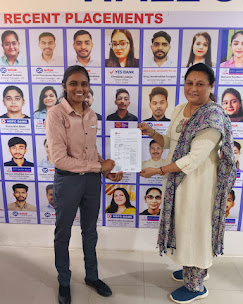 Student receiving placement offer letter in front of Pro IFBI recent placements board