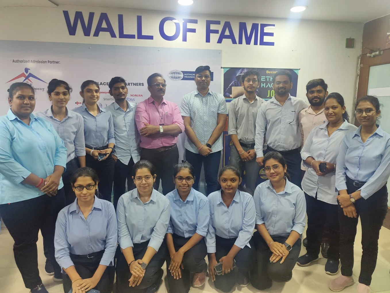 Professional IFBI student batch posing in front of the Wall of Fame board